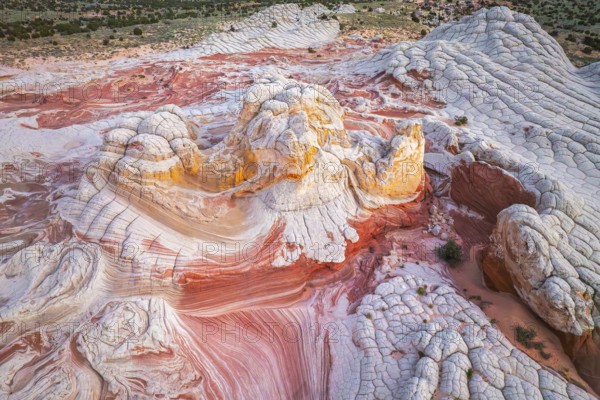 Aerial view of swirling rock formations in vibrant reds and whites in White Pocket, showcasing the