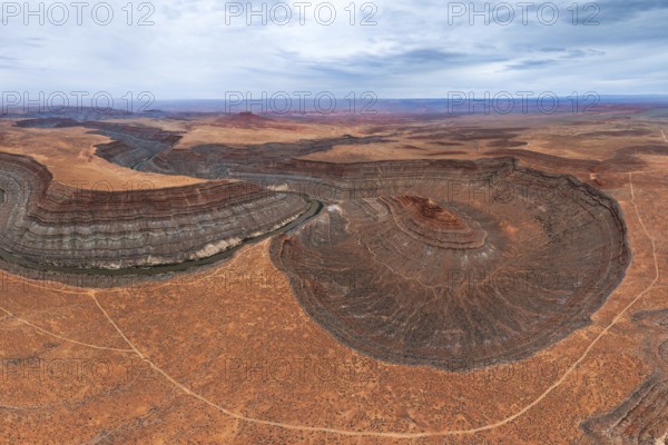 An aerial view showcases a river elegantly meandering through layered rock formations in a vast San