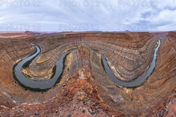 A breathtaking view of a winding river carving through a deep, red rock San Juan canyon, showcasing