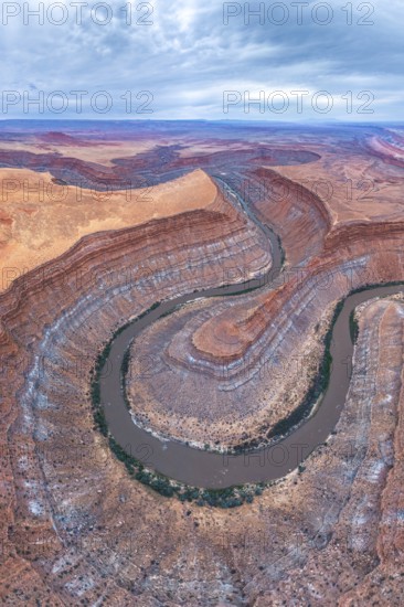 A stunning aerial view captures a serpentine river winding through layered rock formations in a
