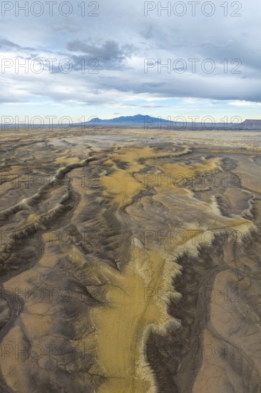 Aerial view of an expansive desert terrain featuring rugged formations and soft sand hues in