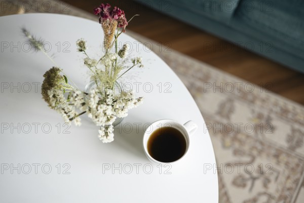 Top view of a serene home scene featuring a cup of black coffee and a vase of delicate dried