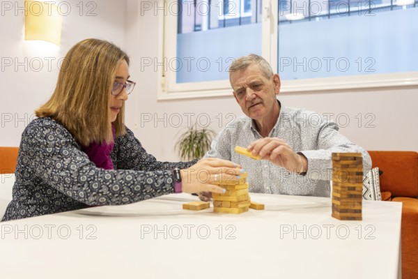 A couple with intellectual disabilities play a block stacking game together at a table of a