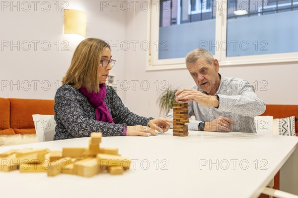 A couple with intellectual disabilities engaged in a game with wooden blocks on a table of a