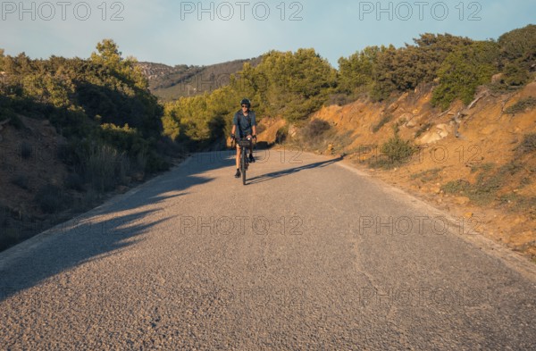 Male cyclist descending a lush mountain road, located in Zahara de los Atunes, Cadiz, capturing the