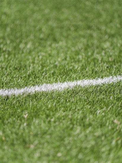 A close up image of a lush green grass soccer field featuring a white boundary line. The vibrant