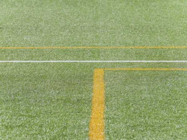 A close up view of vibrant green artificial turf with distinct yellow and white lines, creating
