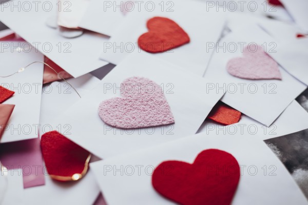 A variety of red and pink felt hearts adorn envelopes, evoking a romantic Valentine's Day