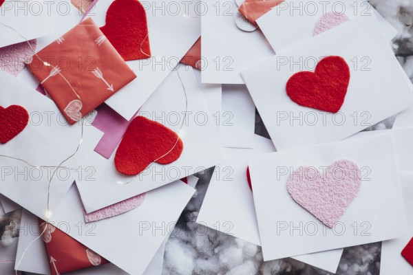 Valentine's Day envelopes adorned with red and pink felt hearts, scattered elegantly among fairy