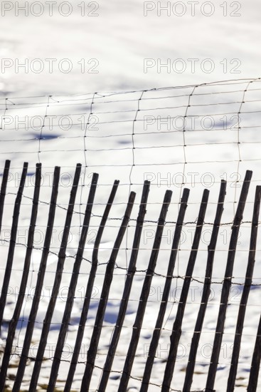 A rustic wooden fence stands in contrast against a serene snowy backdrop, showcasing a blend of