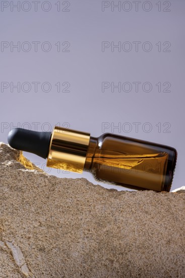 A high-angle shot of an elegant amber glass cosmetic dropper bottle elegantly placed on a textured