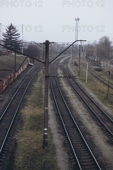 Overhead view of curved railway tracks in a misty, overcast setting. The tracks run alongside a