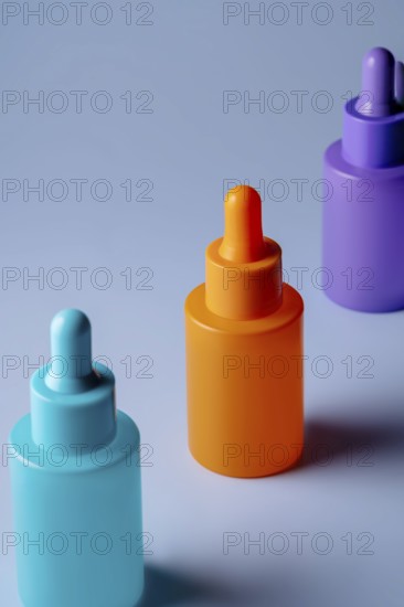 A set of brightly colored serum bottles in orange, purple, and blue against a soft blue background,