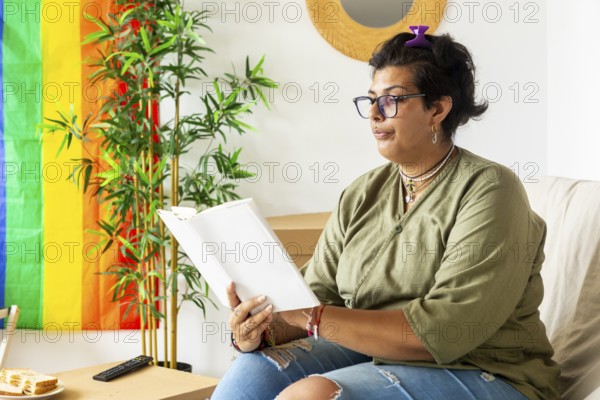 A trans woman enjoys a serene moment, sitting comfortably in her new home, reading a book. The