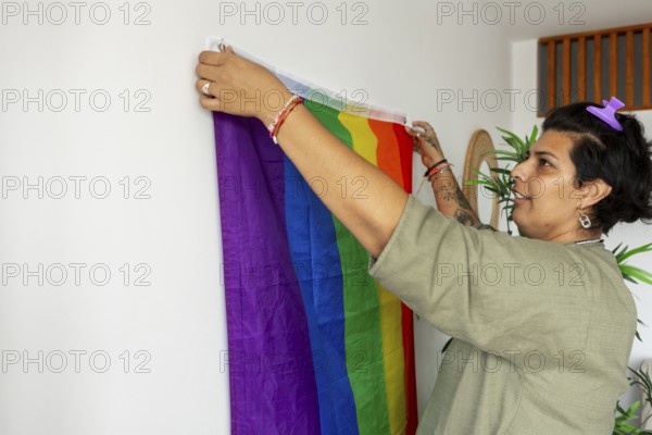 A trans woman joyfully decorating her new home with a rainbow pride flag, symbolizing LGBTQIA+