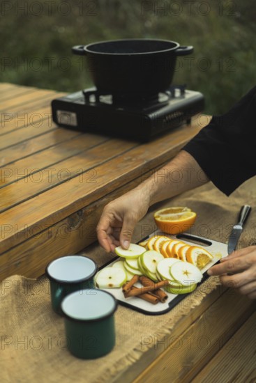 Cropped unrecognizable person preparing ingredients for mulled wine outdoors, arranging sliced