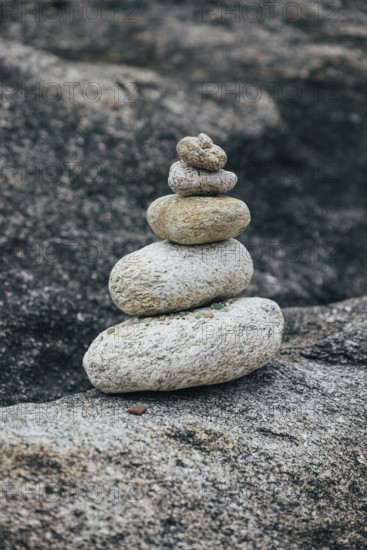 A stack of balanced stones sits on a rocky surface in a peaceful outdoor environment. The image