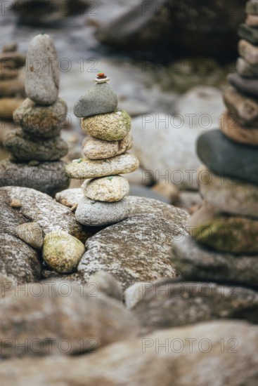 A stack of balanced stones on a rocky surface in a peaceful outdoor setting besides the sea.