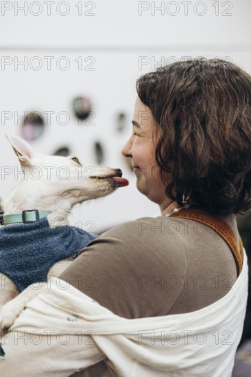 A young woman shares a joyful moment with her dog as it playfully licks her face in a bookstore.