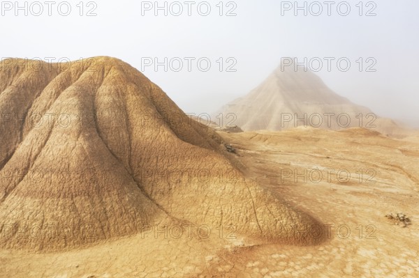A captivating desert scene with majestic eroded hills shrouded in light mist, creating a mysterious