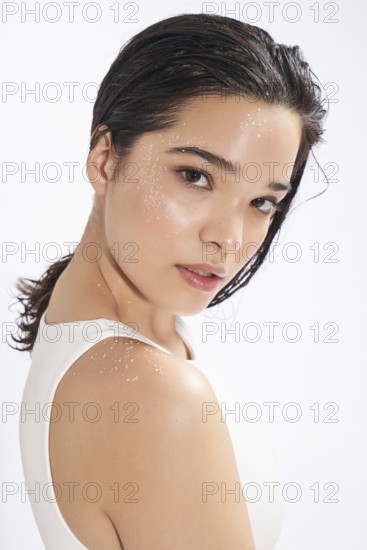 A young woman looks slightly away from the camera in this fresh studio portrait, highlighting her