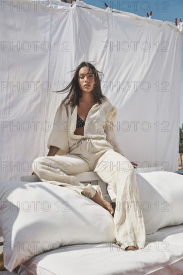 A young woman lounges on a rooftop, basking in the warmth of summer sun Dressed in light, flowing