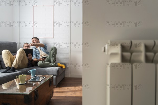 A gay couple enjoying a relaxing day at home, sitting on a comfortable sofa while engaging with