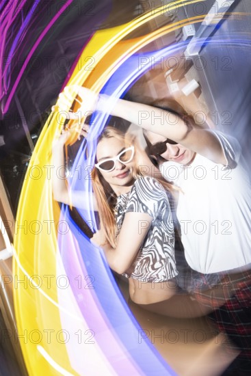 A vibrant party scene features a dynamic lesbian couple dancing energetically, surrounded by