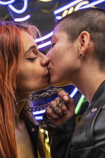 A close-up photo of a lesbian couple kissing passionately, illuminated by vibrant neon lights,