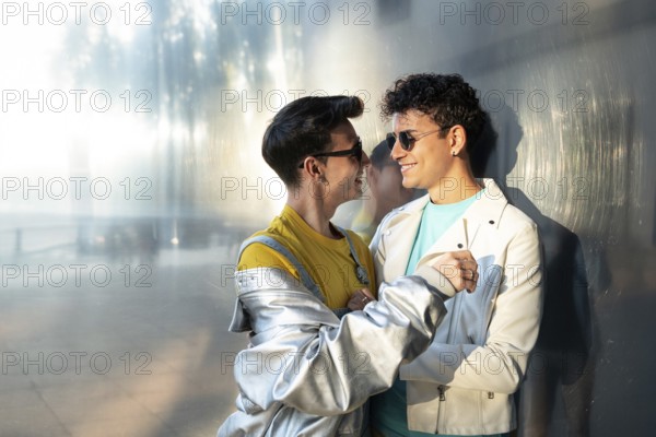A joyful gay couple, wearing casual clothes and sunglasses, share a tender moment while smiling at