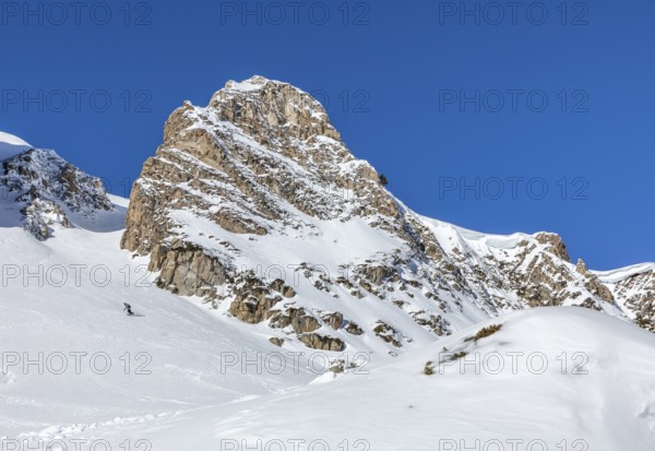 A stunning snow covered mountain peak under a clear blue sky, perfect for winter adventures and the