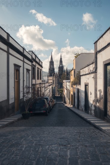 A calm cobblestone street lined with traditional houses leads to the iconic San Juan Bautista