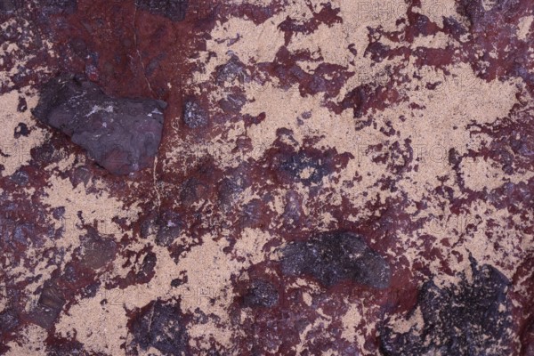 Close-up of the intricate textures of volcanic rocks surrounded by scattered sand at La Pared,