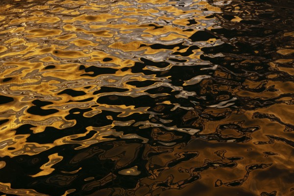 Artistic close-up of shimmering water reflecting golden hues under sunlight at Playa Blanca Port,