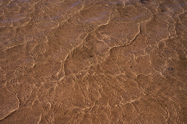 Close-up of the intricate patterns created by sunlight on the rippling shallow waters at La Pared,