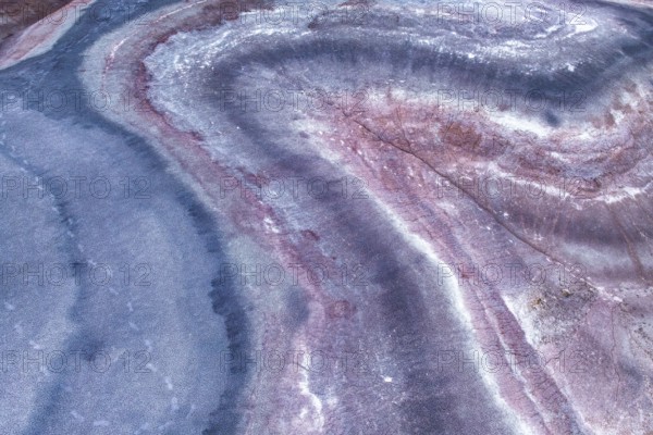 Close up of an sandstone surface, showcasing wavy patterns in pink and blue hues. The intricate