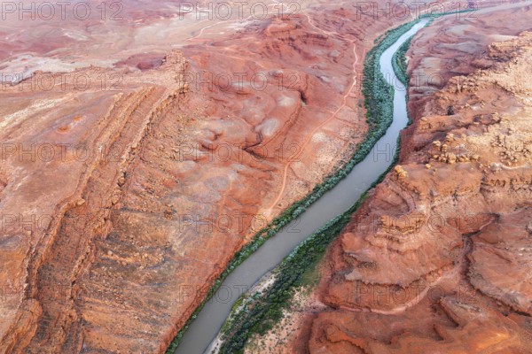 Aerial shot displays the meandering Rio San Juan snaking through vibrant red, rocky terrains of