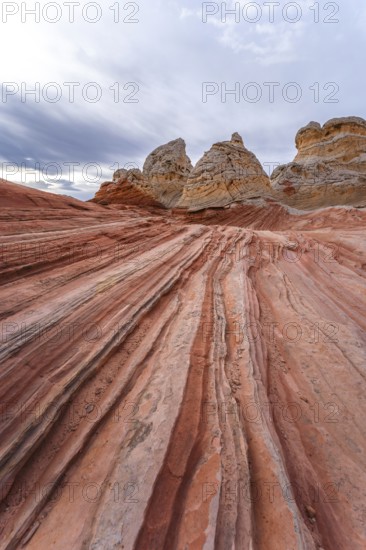 Vibrant and textured red rock formations stretch under a cloudy sky at White Pocket in Arizona,