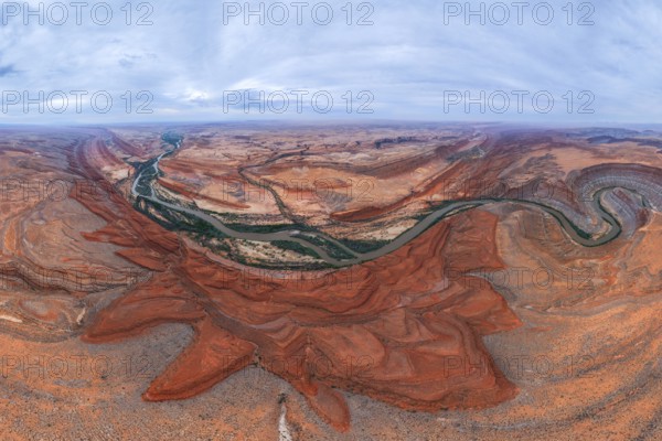 A breathtaking aerial view of a desert landscape. A winding river cuts through red rock San Juan