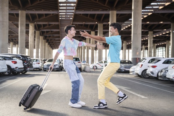 A cheerful gay couple reunites in a spacious parking lot, one carrying a suitcase. They are