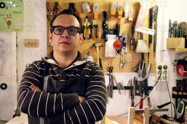 A luthier stands confidently in a bass guitar workshop, surrounded by tools and equipment. The