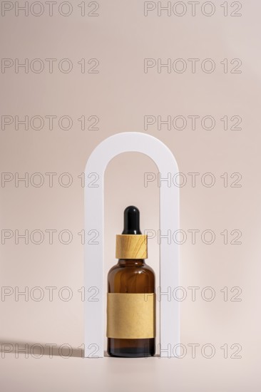 An amber glass dropper bottle with a wooden cap and blank label is elegantly placed in a white arch