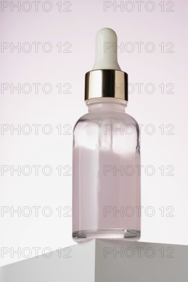 An elegant dropper bottle for cosmetics prominently displayed on a two toned minimalist podium,