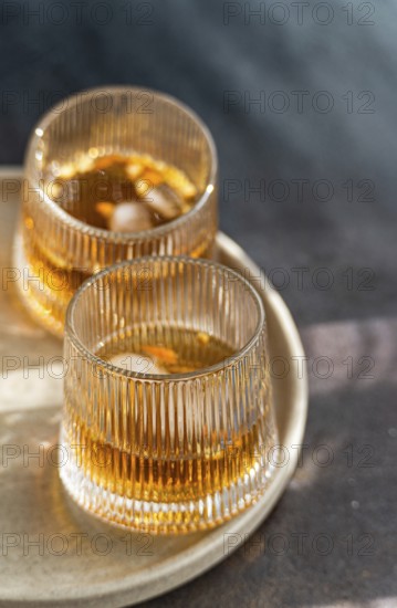 Two glasses of spiced cognac cocktail with cinnamon and star anise, accompanied by assorted nuts,