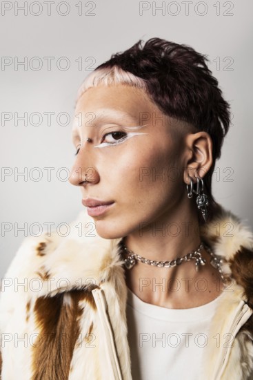 Wide angle close-up of a woman with a bold hairstyle, glamorous nose and ear piercings, striking