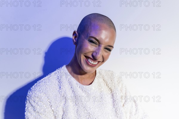 A middle-aged woman with a shaved head smiles confidently, reflecting self-assurance and