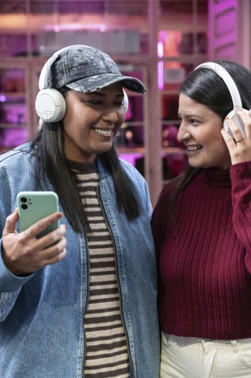 A joyful Latin couple shares a moment, smiling and listening to music with headphones. Their casual