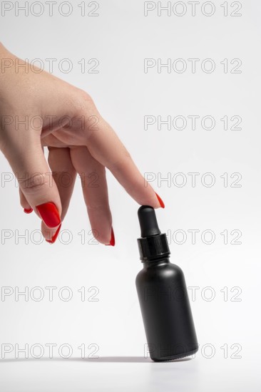 Cropped unrecognizable female hand with vibrant red manicure gracefully touching a sleek black