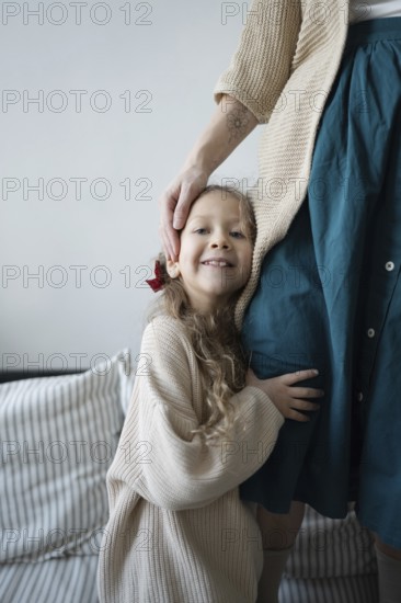 A young girl smiles while hugging her mother, showcasing a sense of warmth and security The scene