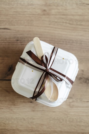 Top view of an elegantly packaged bento birthday cake, tied with a brown satin ribbon and wooden
